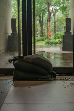 Sandbags stacked at glass entrance gate for flood prevention in rainy building lobby