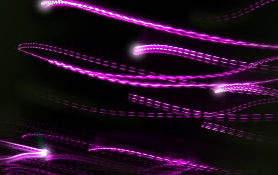 Abstract light trails on a black background with a motion blur effect. Neutral graphic background.