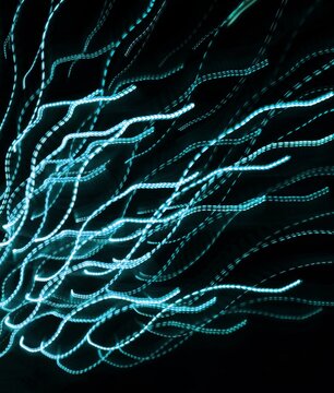 Abstract light trails on a black background with a motion blur effect. Neutral graphic background.