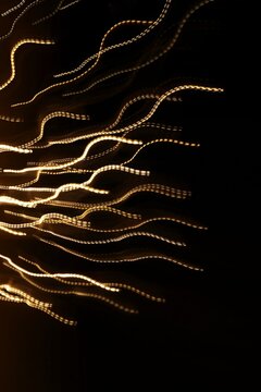 Abstract light trails on a black background with a motion blur effect. Neutral graphic background.