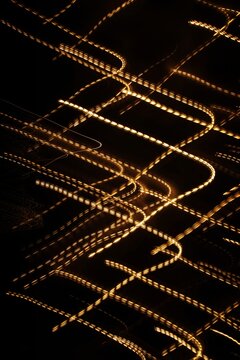 Abstract light trails on a black background with a motion blur effect. Neutral graphic background.