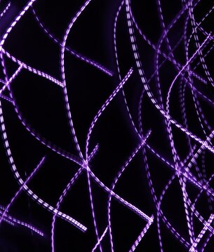 Abstract light trails on a black background with a motion blur effect. Neutral graphic background.