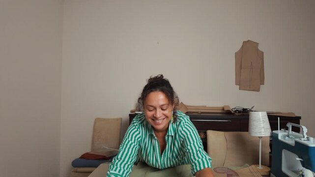 A woman tailor working with fabric patterns on a table.