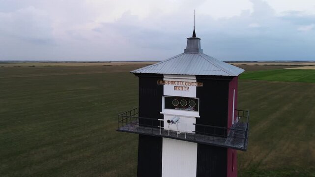 Drone flying around the historical Shabla Lighthouse in Bulgaria showcasing its architecture and surrounding green fields