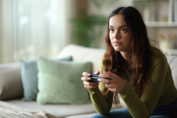 Concentrated teenage girl playing video game using controller © PheelingsMedia