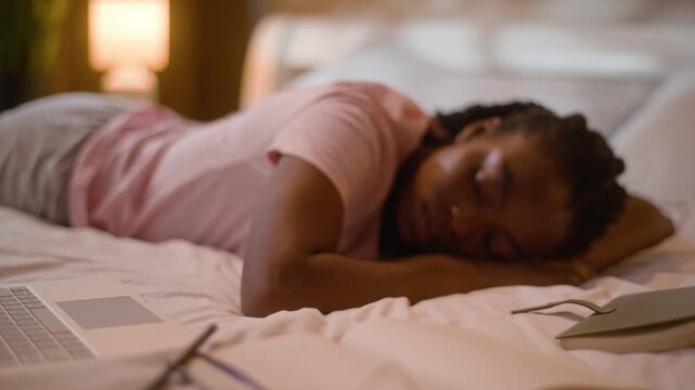 Relaxed African American woman sleeping dont hear mobile phone call on bed at home late evening female student study reading book napping tired girl dreaming sleep miss notification nap bedroom indoor