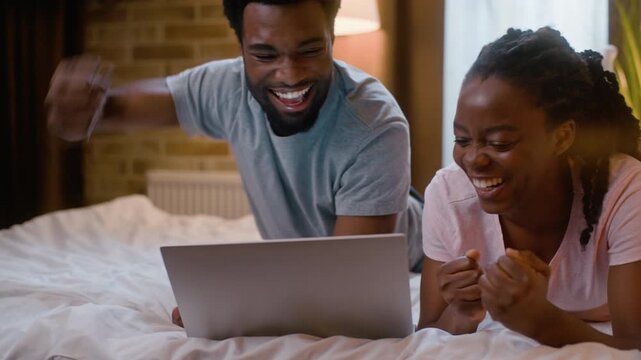 Happy cheerful African American couple celebrating sports victory on tablet home bedroom evening joyful family giving high five gesture winning online betting game success lucky female male win cash