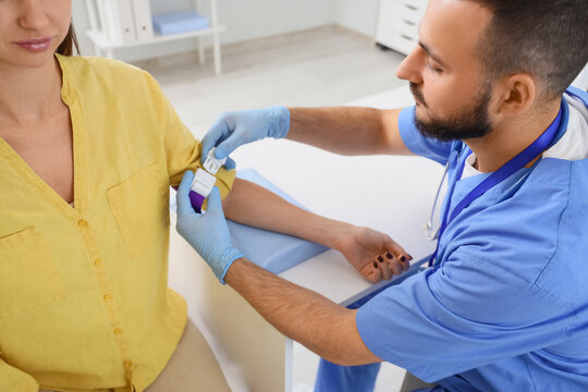Blood test and medical examination, male nurse applying a tourniquet on a female patient arm for health checkup in a clinic