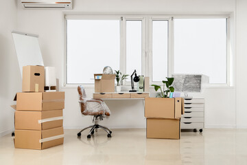 Obraz na płótnie Canvas Corporate downsizing and office relocation, cardboard boxes and packed furniture in an empty workspace during business move or company restructuring