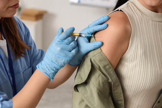 Vaccination and immunization, nurse giving a flu shot injection to a patient in a medical clinic for disease prevention and public health care