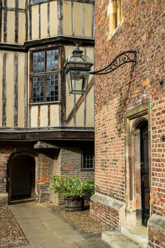 Historic English Tudor Courtyard with Vintage Lantern, Red Brick Wall, and Half-Timbered Architecture