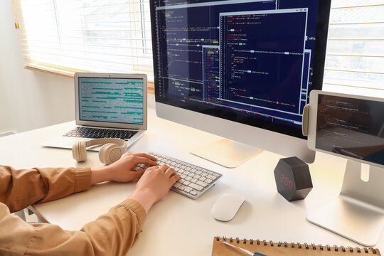 Software development and coding, programmer working on computer programming project with multiple screens and laptop in a modern home office workspace