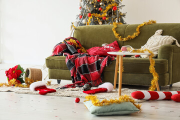 Fototapeta premium Post-party cleanup, messy living room after Christmas celebration with empty wine bottles and scattered holiday decorations on a green velvet sofa