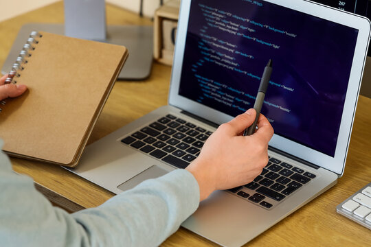 Software development and coding education, programmer working on laptop with source code and notebook at desk for computer science learning and training