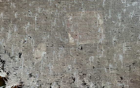 torn and damaged old window screen mesh texture, abstract background of broken wire net