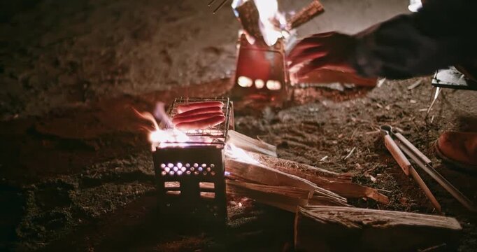 夜のキャンプでウインナーを焼いている風景