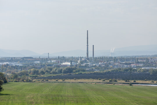 01 October 2026, Panoramic view of the industrial city of Chomutov featuring factory chimneys and solar farms, Chomutov, Czech Republic.