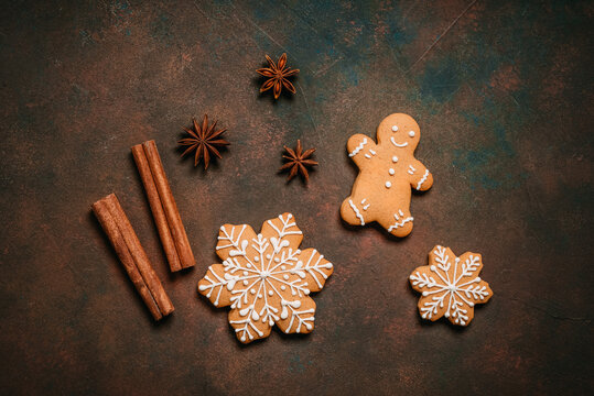 Gingerbread man and snowflakes on dark rustic background, top view, flat lay