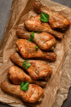 Roasted chicken drumsticks on paper, dark rustic background, top view, flat lay, copy space, vertical