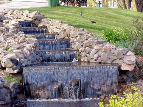 Cascading artificial waterfall with stone tiers in a public park in Riga