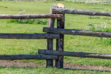 Fototapeta premium Rustic wooden fence stands in lush green pasture