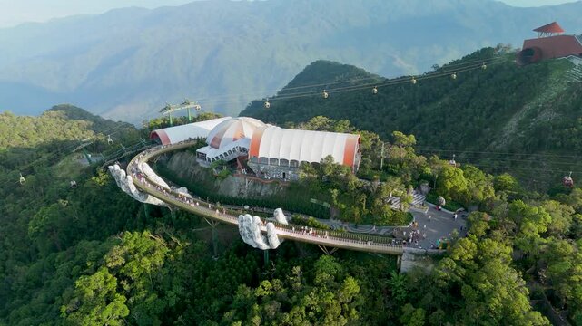 Soaring views capture the iconic architectural marvel of the Golden Bridge nestled high in the tropical mountains of Da Nang where misty peaks touch the sky