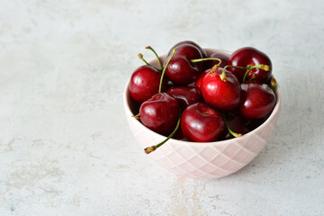 Fresh Cherries in a Bowl on Textured pastel Surface, copy space © Irina