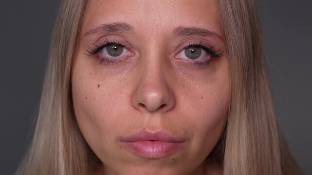 Young woman looks into the camera and blinks in close-up, showing false eyelashes or eyelash extensions and drawing attention to the finished lash effect