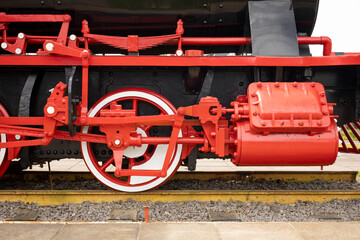 Side view of a historic steam locomotive wheel and red mechanism on tracks. © MARCELO
