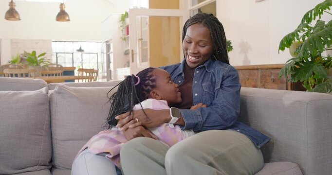 African American mother and child cradling on gray couch, child speaking, denim shirt bonding