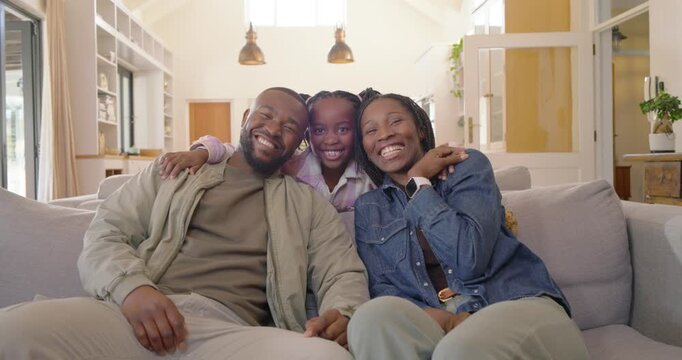 African family daughter scooting closer to parents, leaning in and posing for camera on gray couch
