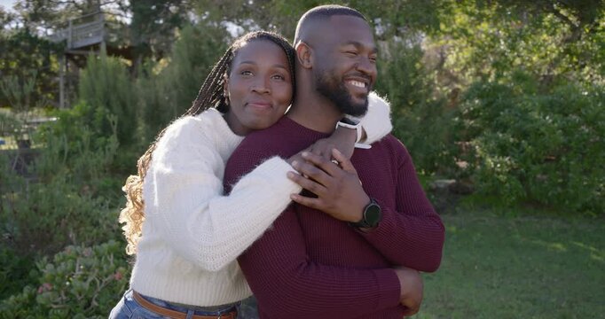 Romantic couple woman approaching, wrapping arms around man holding phone in knits, posing on lawn