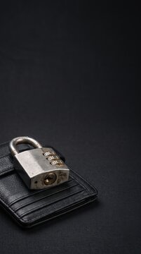 Metal padlock resting on a leather wallet against a dark background. Concept of financial security and mindful spending habits.