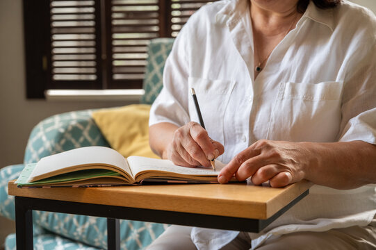 senior woman writing down her memories into a notebook, checking the budget etc copy space banner 
