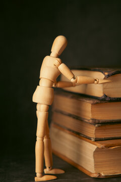 Wooden mannequin and books on black background, closeup