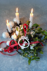 Fototapeta premium Christmas background. candles, decor with angel, christmas balls, ribbons, mistletoe branches on table. Composition for Christmas, Advent, Yule, New Year holidays, festive winter season