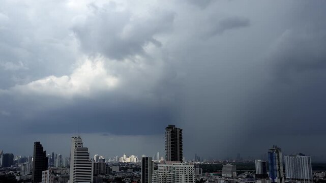 Time-lapse of Heavy rainfall pouring from towering thunderclouds above an urban landscape