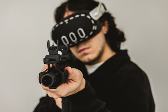 Man wearing virtual reality headset aiming AR-15 rifle controller in VR training simulation