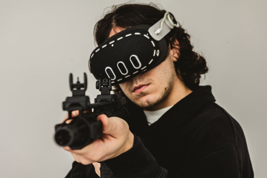 Man wearing virtual reality headset aiming AR-15 rifle controller in VR training simulation