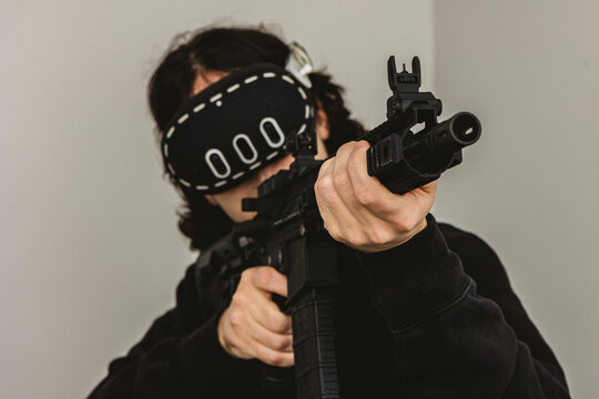 Man wearing virtual reality headset aiming AR-15 rifle controller in VR training simulation