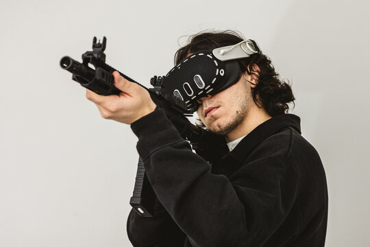 Man wearing virtual reality headset aiming AR-15 rifle controller in VR training simulation