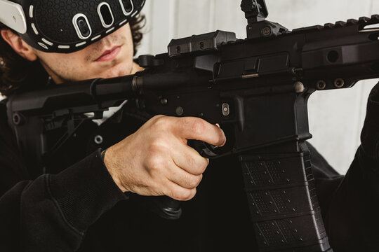 Man wearing virtual reality headset aiming AR-15 rifle controller in VR training simulation