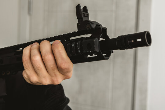 Close up of hand holding AR-15 rifle handguard with flip up sight and muzzle brake