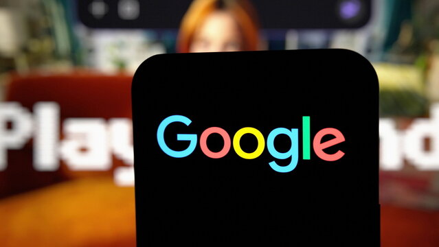 Close-up of the Google logo displayed on a smartphone with an image from the official announcement in the background. October 7, 2026, Lisbon, Portugal.