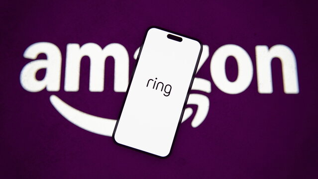 The Ring logo displayed on a smartphone, with a projected Amazon logo. Ring Unveils $249 Smart Lock With Hand-Crank Backup Charging, Five New Cameras. October 8, 2026, Lisbon, Portugal.