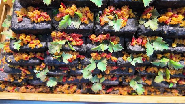 Pyramid of traditional Chinese black stinky tofu with spicy herbs