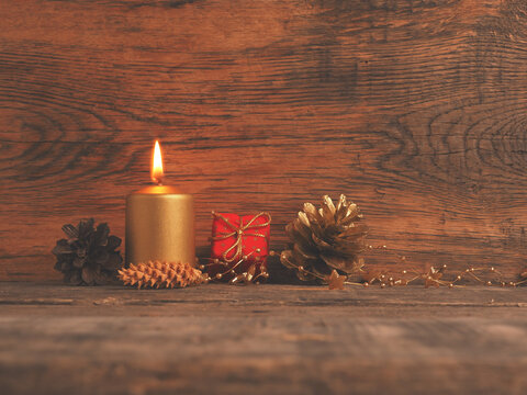 Golden Advent candle on a rustic wooden background, First candle is burning