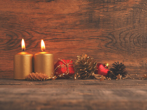 Two Golden Advent candles on a rustic wooden background, second Advent candle is burning