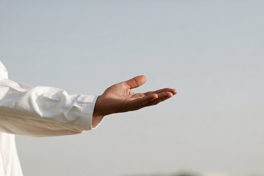 Human hand extended palm up against blue sky