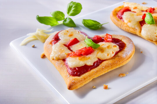 Pizza in Herzform mit Tomaten, Mozzarella und Basilikum